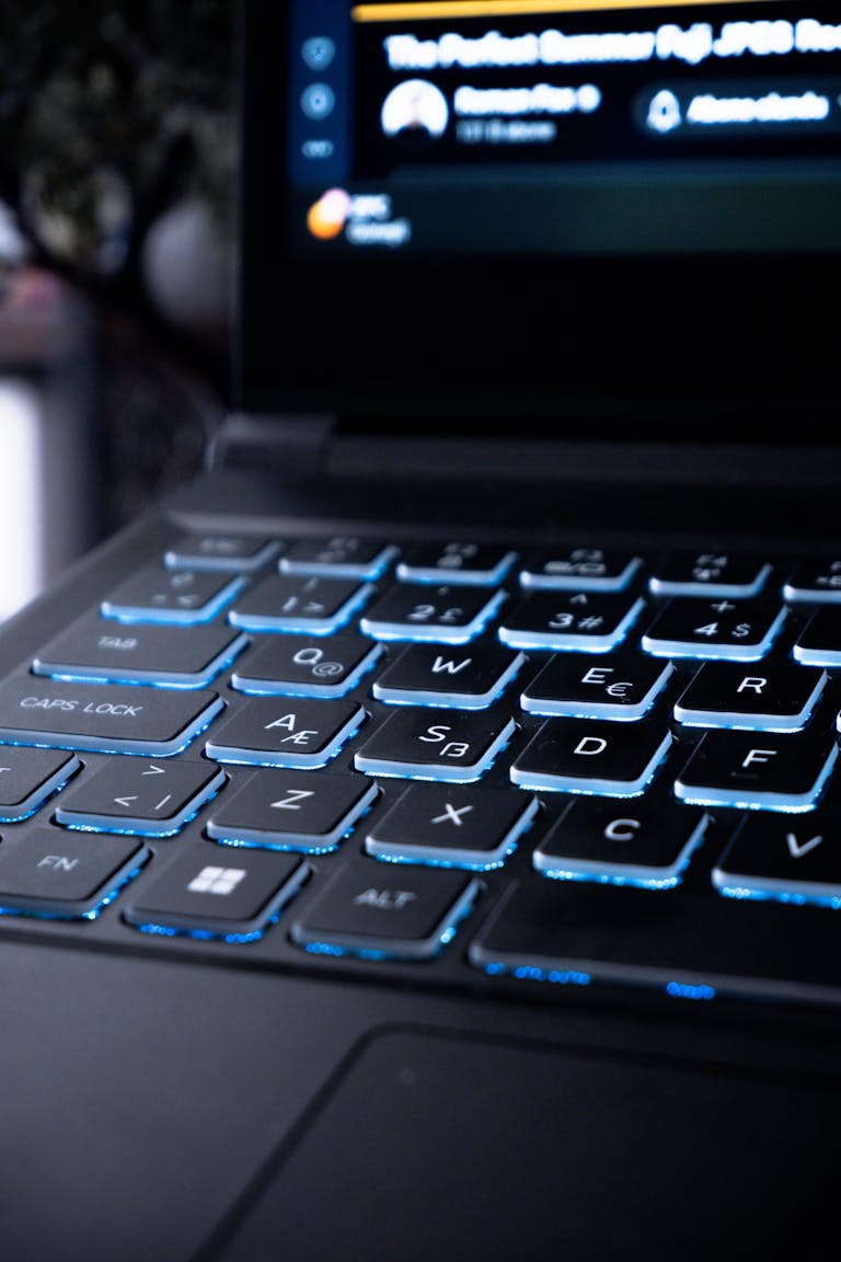 Close-up of a modern gaming laptop keyboard with blue backlit keys, suitable for tech and lifestyle themes.